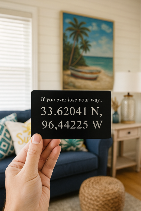 Hand holding a card with GPS coordinates and heartfelt message in a living room with a couch and decorative items.