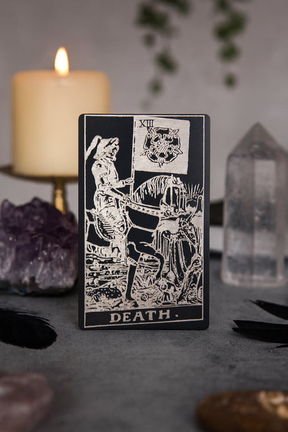 Metal black/silver Tarot card titled 'Death' with a candle and crystals in the background