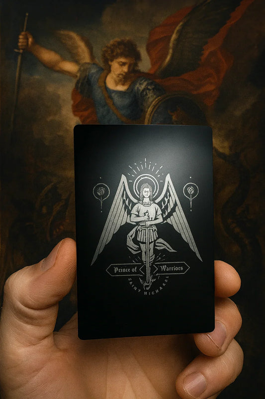 Hand holding a black card with an St Michael angelic design against a dark background