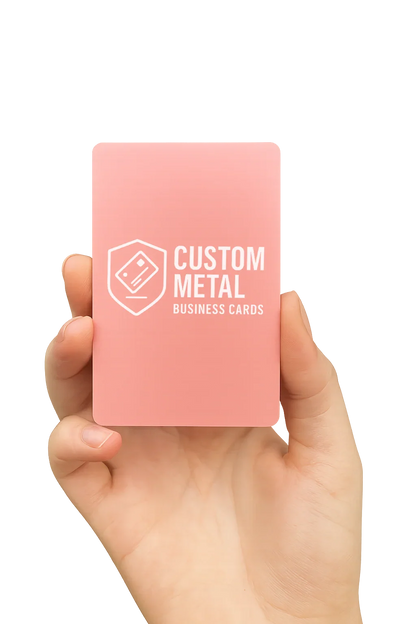 Hand holding a pink card with 'Custom Metal Business Cards' text on a white background