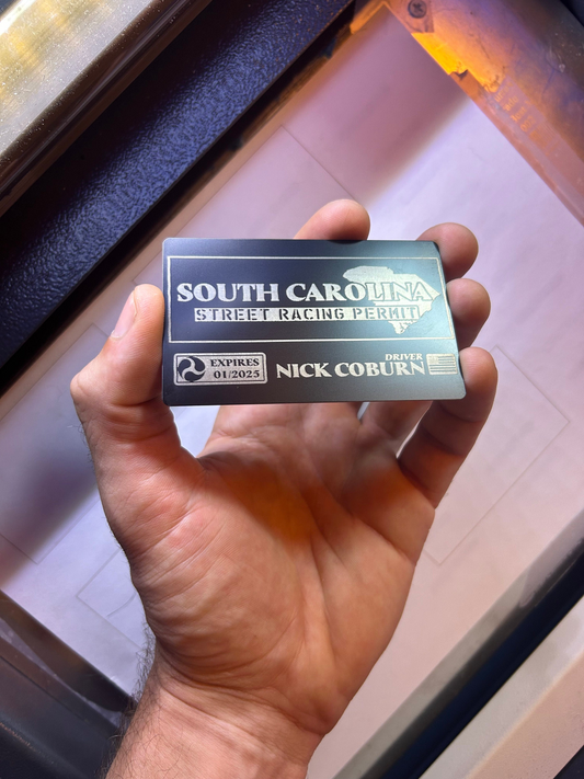 Hand holding a metal South Carolina Street Racing Permit card with a blurred background