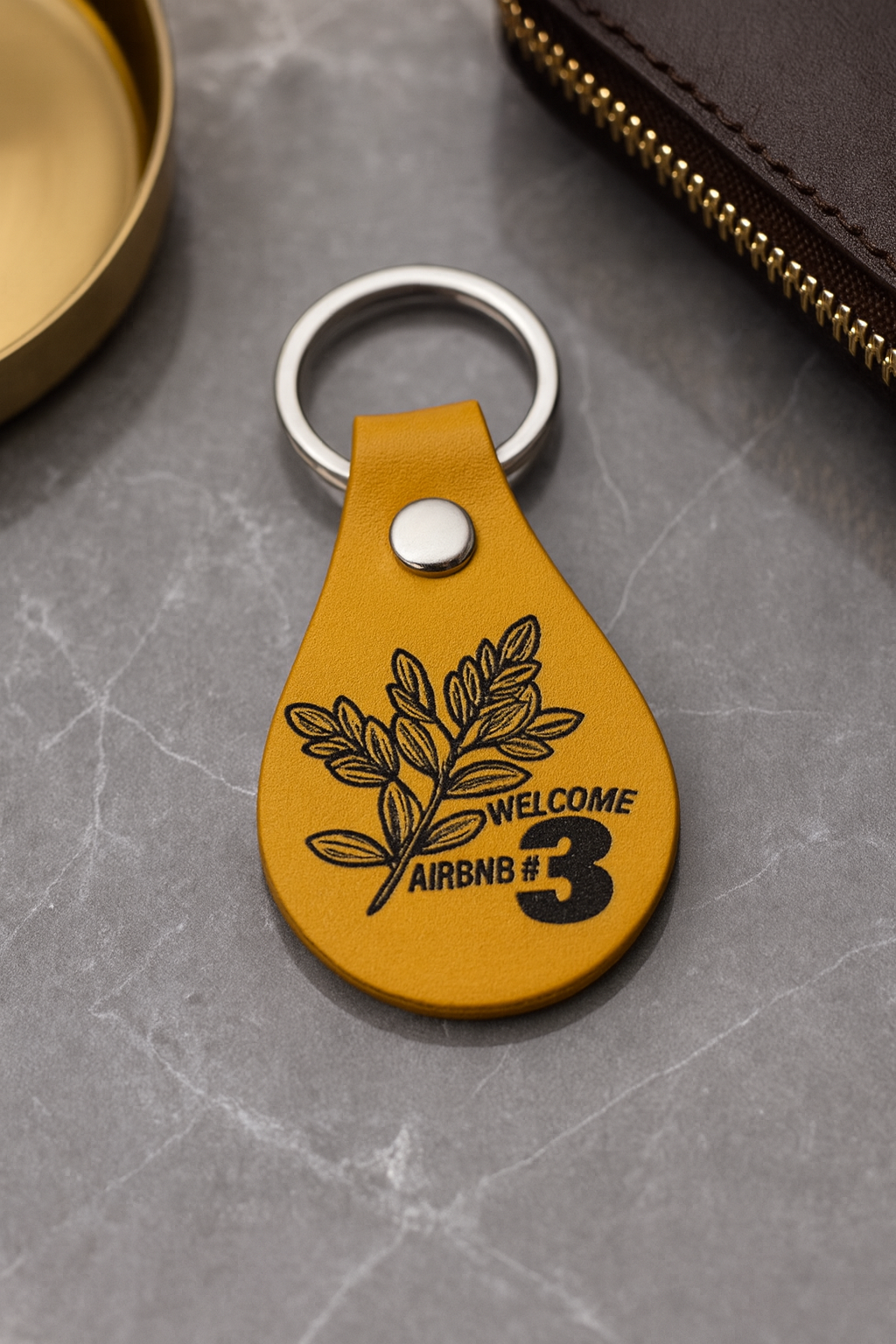 Yellow leather keychain fob with engraved text on a gray surface